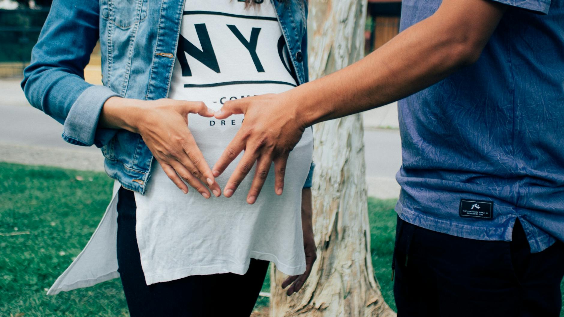 pregnant woman holding her tummy together with a man beside