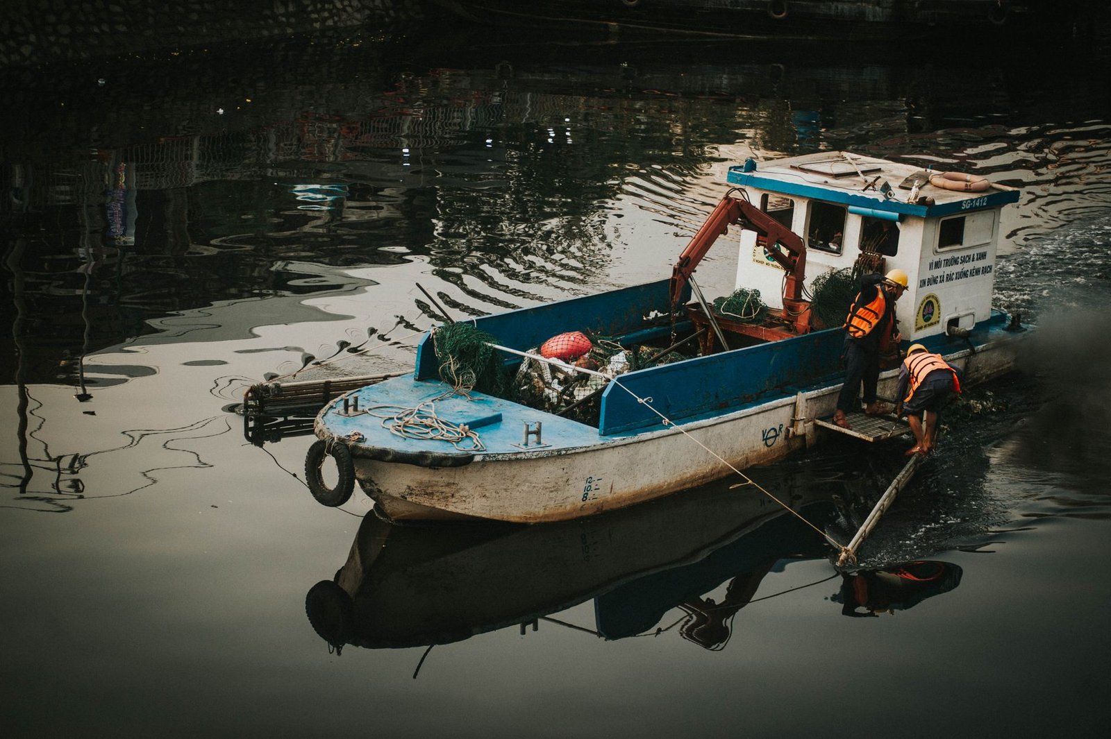 men in the boat cleaning the trashes in the water