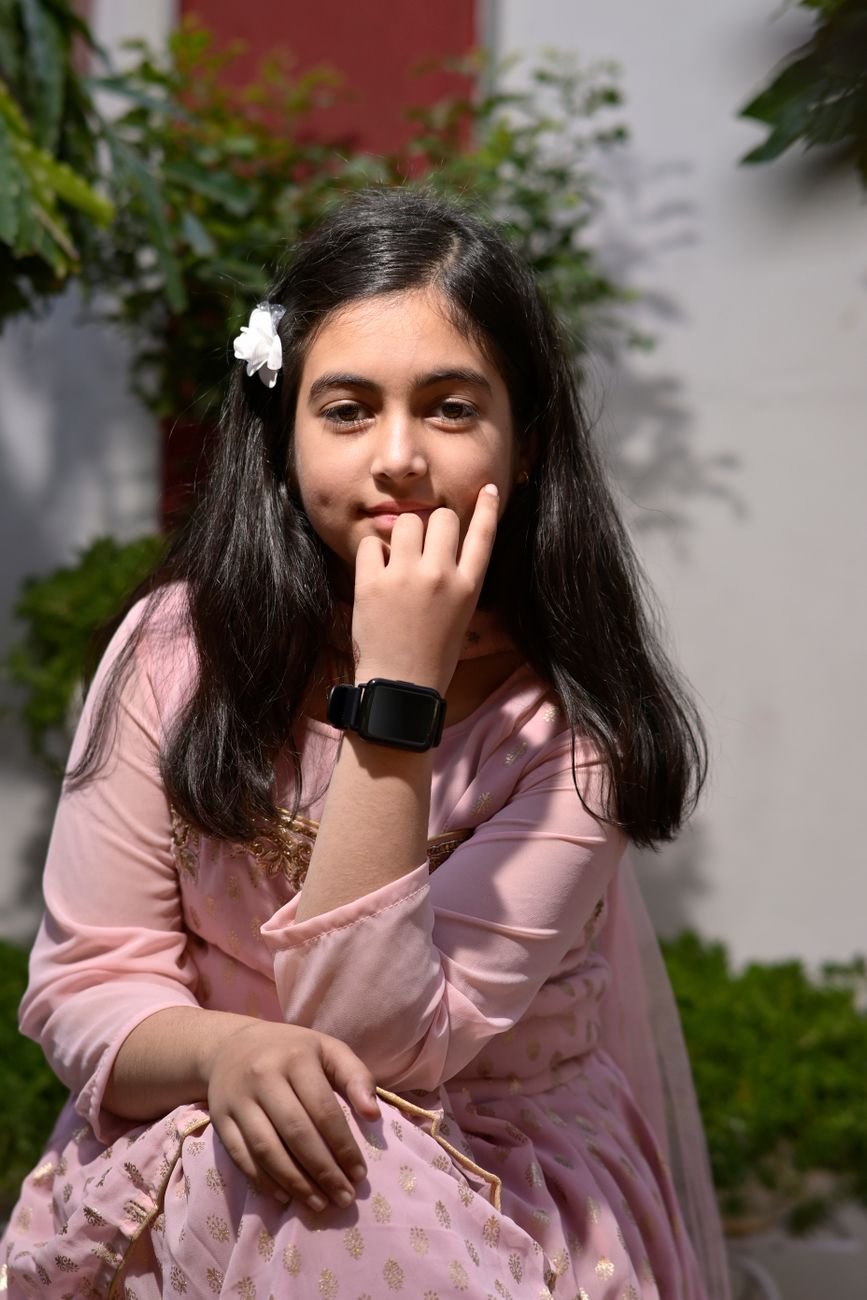 charming girl in pink dress with smartwatch outdoors