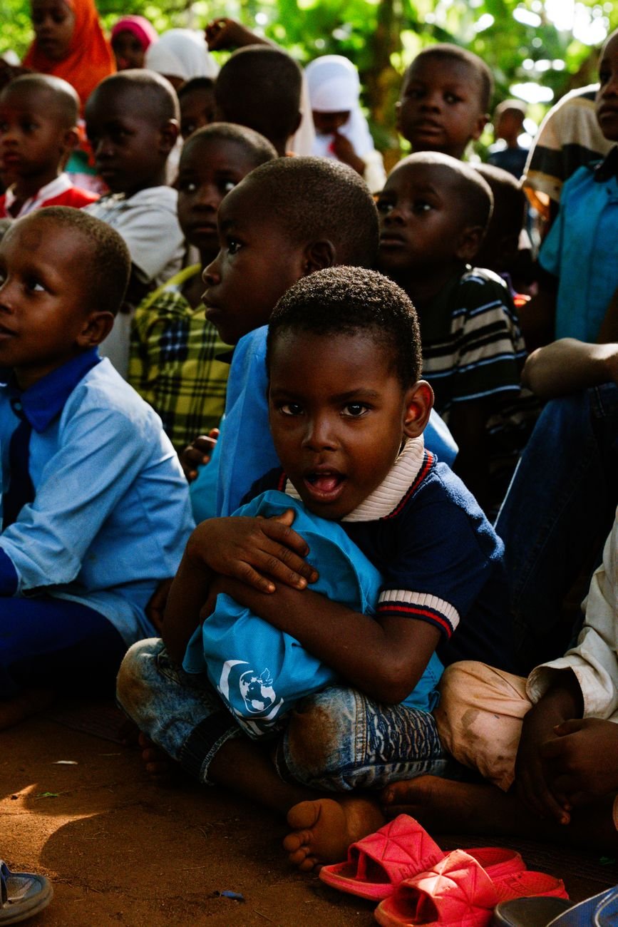 group of children sitting outdoors in shade
