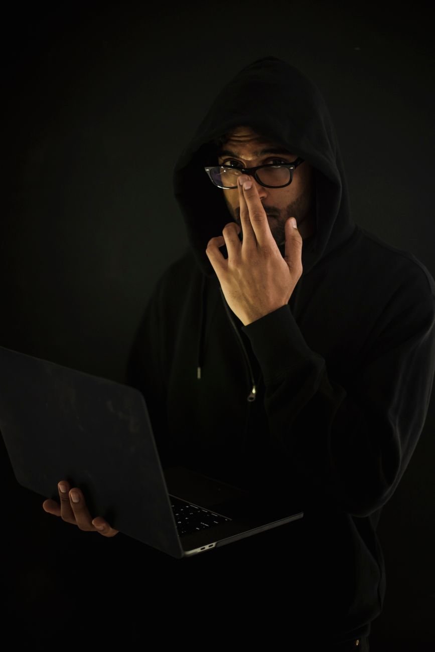 male computer geek in eyeglasses with laptop in darkness